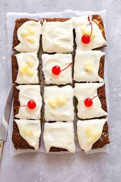 slices of cake with white frosting and cherries on top next to a knife