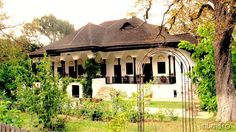 an old white house surrounded by trees and greenery