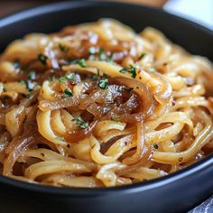 a black bowl filled with pasta and onions