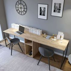 a desk with two chairs and a clock on the wall above it in a living room