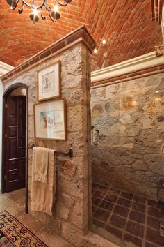 a bathroom with a brick wall and chandelier hanging from it's ceiling