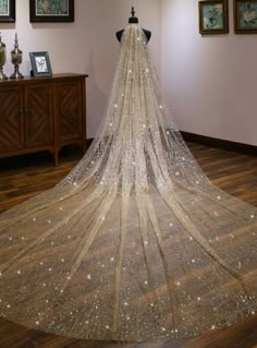 the back of a wedding dress with sequins and beads on it, hanging from a mannequin's head