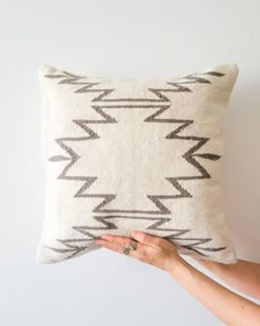 a woman is holding up a pillow with an arrow pattern on it