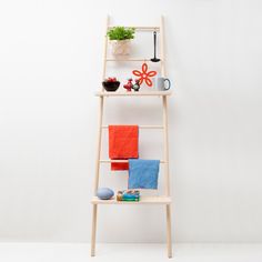 a wooden shelf with towels, cups and plants on it next to a white wall