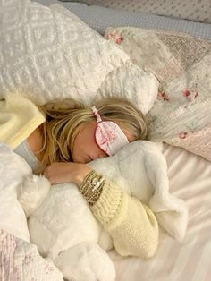 a woman laying in bed with a white teddy bear