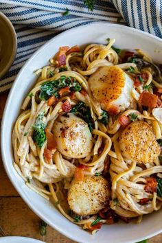 pasta with scallops and spinach in a white bowl on a wooden table