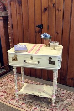 an old white table with flowers on top in front of a wood paneled wall