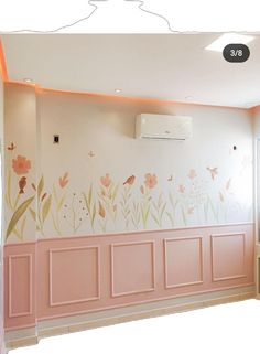 an empty room with pink walls and flowers painted on the wall, along with a air conditioner