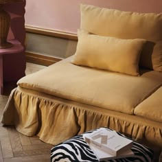 a bed with two pillows on top of it and a zebra print footstool