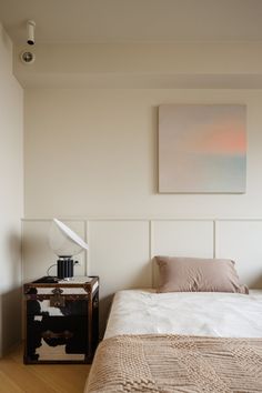 a bed sitting in a bedroom next to a painting