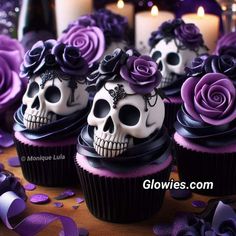 cupcakes decorated with sugar skulls and purple roses are sitting on a table next to candles