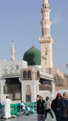 many people are walking around in front of a building with a green dome on top