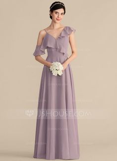 a woman in a long purple dress with flowers on the waist and shoulder, standing against a