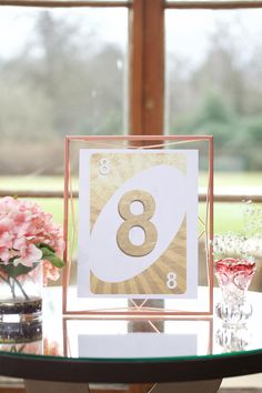 a table with a card and vases filled with pink flowers on top of it