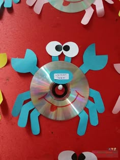 a red table topped with cds and paper cut out like crabs on top of each other