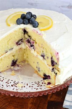 a white cake with blueberries and lemons on top is cut in half to show the inside