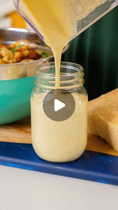 a person pours dressing into a jar on a cutting board with bread and butter