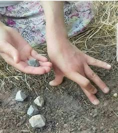 someone is holding rocks in their hands on the ground