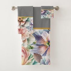 two towels with flowers on them hanging from a towel rack in front of a white wall