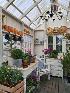 a room filled with lots of potted plants inside of a greenhouse type building next to a wooden floor