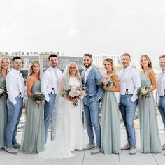 a group of people standing next to each other on top of a roof with buildings in the background