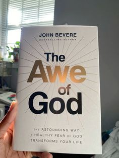 a person holding up a book about the awe of god