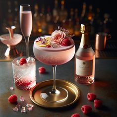 a table topped with two glasses filled with liquid and raspberries next to bottles