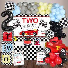 a table topped with balloons and decorations next to a sign that says two for cars