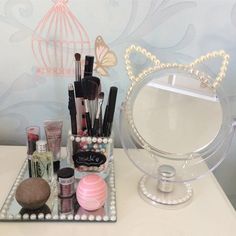 a vanity mirror with makeup and other items on it next to a decorative birdcage