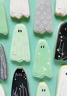 decorated cookies in the shape of ghostes on a green surface