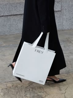 a woman carrying a shopping bag with the word frey on it's side