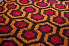 a crocheted blanket with red and black hexagons