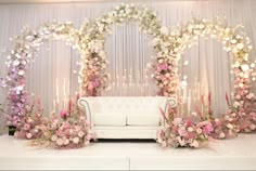 a white couch sitting in front of a flower covered stage with flowers on the wall