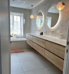 a bathroom with two sinks and mirrors in the wall above it is also a bathtub