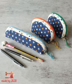 three pencils, two pens and an empty zippered pouch sitting on a table