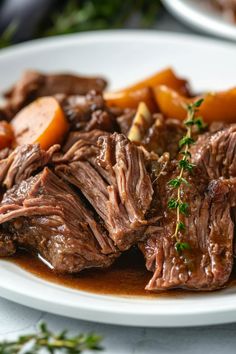 a white plate topped with beef and carrots covered in gravy on top of a table