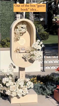 a sign that says out of the box guest book idea with flowers in front of it