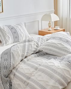 an unmade bed with white and black striped comforter