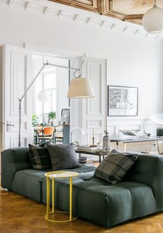 a living room filled with furniture next to a table and lamp on top of a hard wood floor