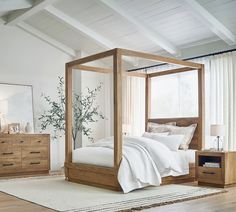 a bedroom with a canopy bed, dressers and mirror on the wall next to it