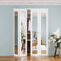 an empty room with blue walls and wooden floors is shown in the foreground, there are two vases filled with flowers