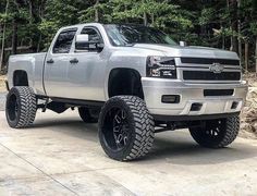 a silver truck is parked in front of some trees