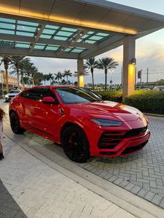 a red sports car parked in front of a gas station with people walking by it