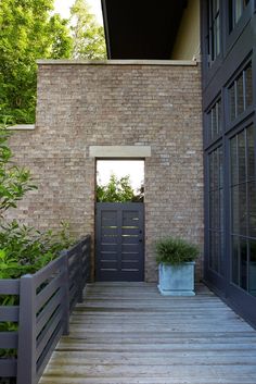 an entrance to a brick building with a planter on the outside and wooden walkway