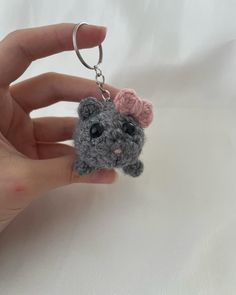 a small gray teddy bear with a pink bow on it's head is being held by a person