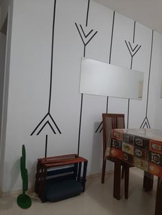 a table and chairs in front of a wall with arrows painted on it, next to a mirror