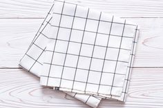 two white and black napkins sitting on top of a wooden table next to each other