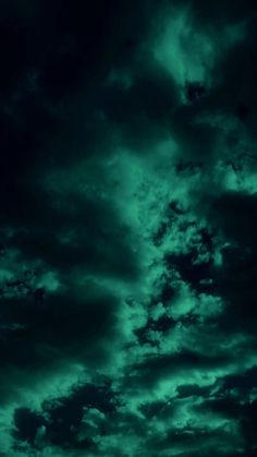 the sky is filled with dark clouds and green hues