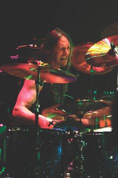 a man with long hair playing drums on stage