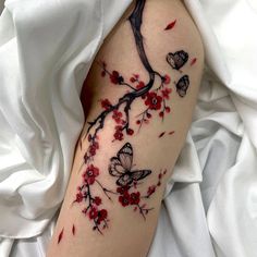 a woman's arm with red flowers and butterflies on it